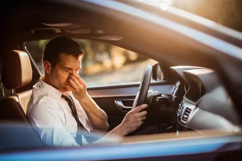 Mann sitzt erschöpft im Auto