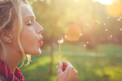 Frau pustet Pusteblume