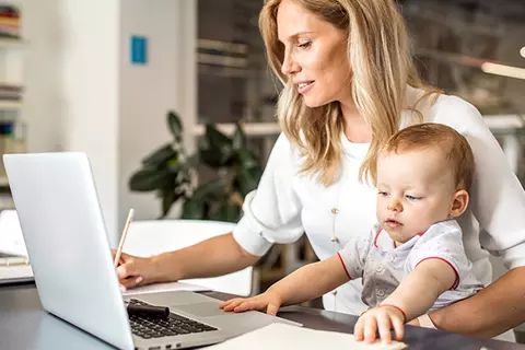 Mutter arbeitet mit Baby im Arm
