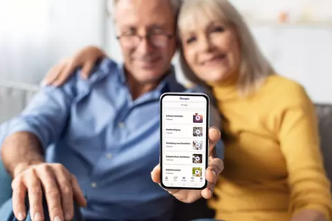 Ein glückliches Pärchen auf dem Sofa zeigen das Bild auf dem Handy