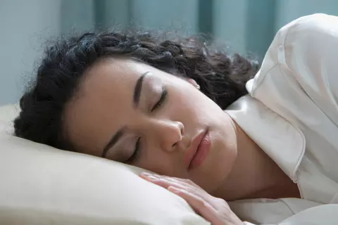 Eine Frau, die ihre Schlafstörungen durch eine gute Schlafhygiene überwunden hat.