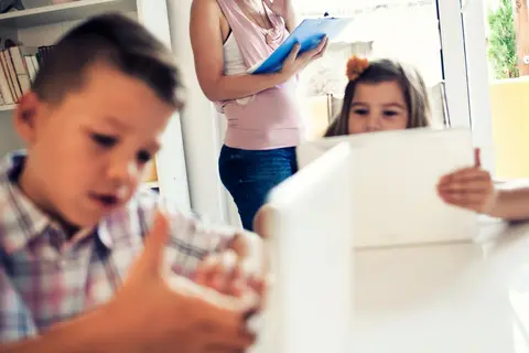 Eine Frau arbeitet zu Hause, während ihre Kinder herumtollen.