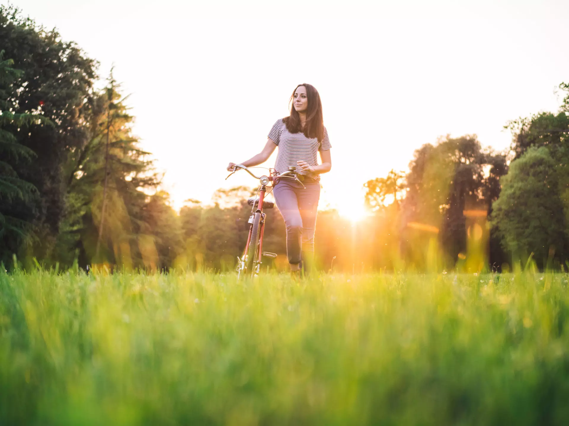 Frau schiebt Fahrrad über eine Wiese