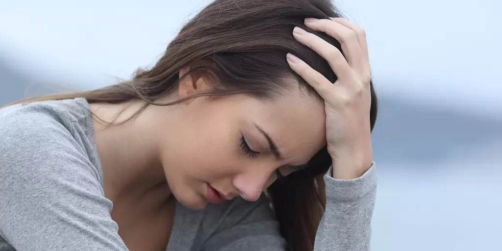 Frau legt verzweifelt Kopf in die Hand