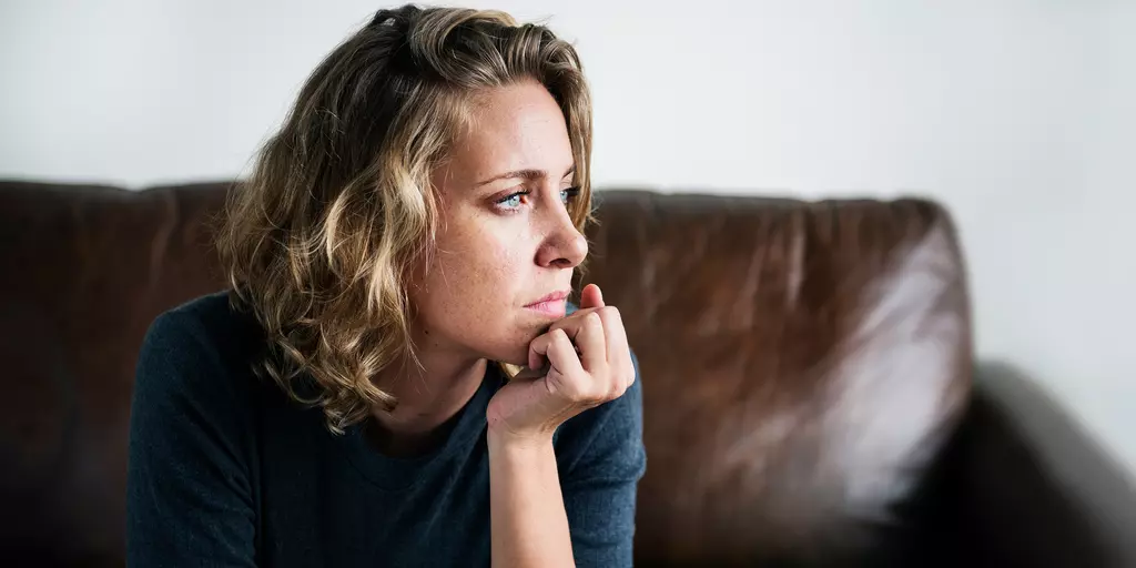 Frau sitzt nachdenklich auf dem Sofa