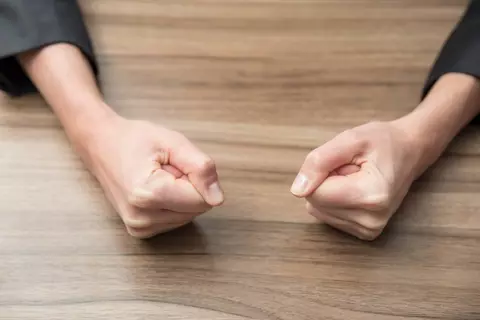 Zwei geballte Fäuste auf Tisch