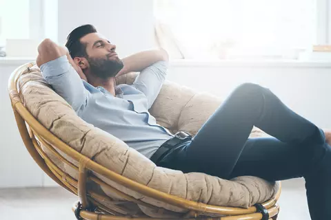 Mann sitzt entspannt im Sessel