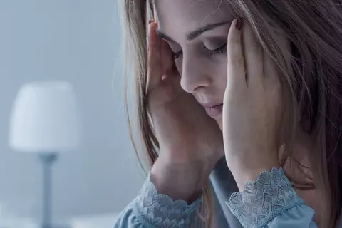 Frau legt verzweifelt Kopf in die Hand