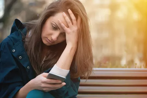 Frau blickt angespannt auf ihr Smartphone