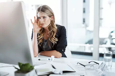 Angestellte schaut gestresst auf den Computerbildschirm