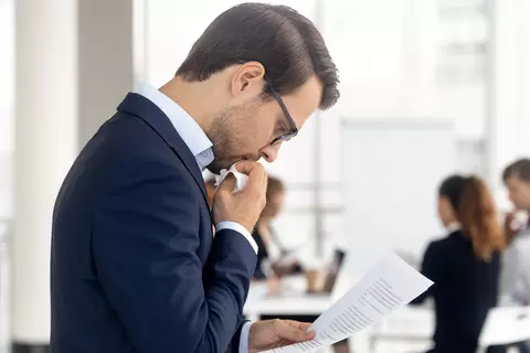 Mitarbeiter greift sich nachdenklich an sein Kinn