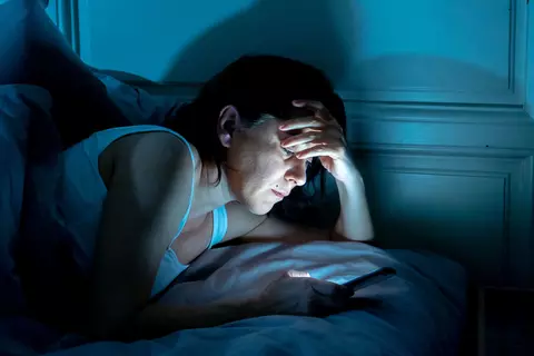Frau nutzt Handy im Bett