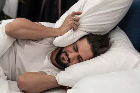 Mann vergräbt sich in Kopfkissen