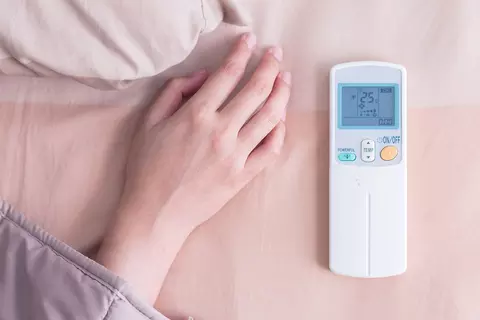 Hand neben einer Fernbedienung, die die Temperatur regelt
