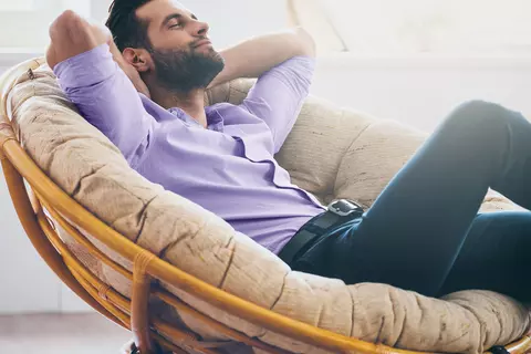 Mann sitzt entspannt im Sessel