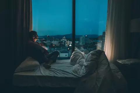 Mann sitzt nachts im Bett und schaut aus dem Fenster