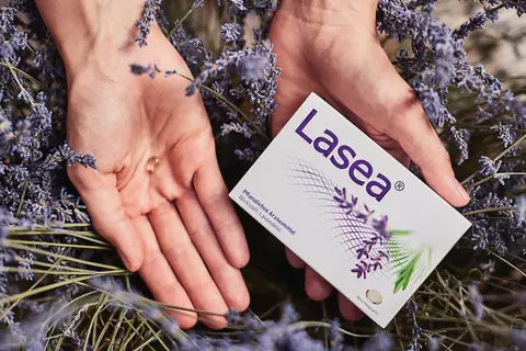 Lasea Packung in Lavendelfeld mit einer Lasea Kapsel in der Hand