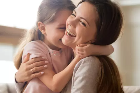 Lächelnde Mutter mit ihrer Tochter auf dem Arm