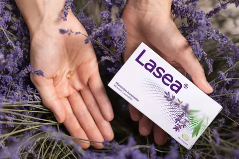 Lasea Packung in Lavendelfeld mit einer Lasea Kapsel in der Hand