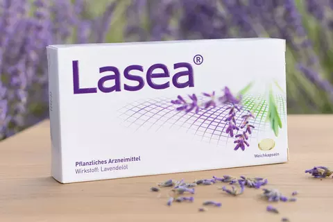 Lasea Packshot mit Blüten vor der Packung auf Holzuntergrund