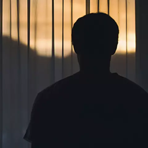 Mann schaut nachts aus dem Fenster