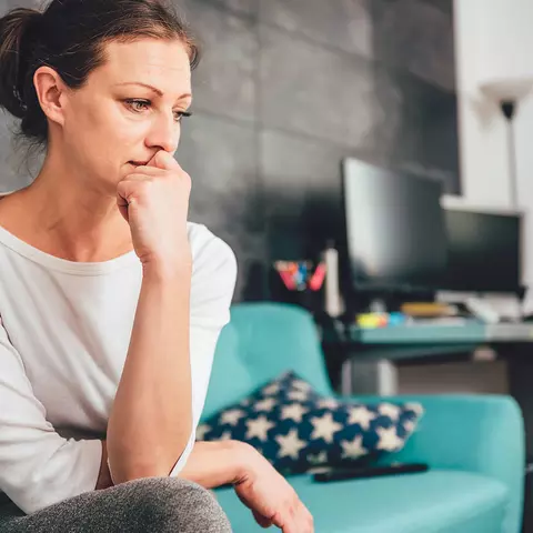 Frau sitzt nachdenklich auf dem Sofa