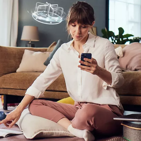 Mutter mit Kind im Wohnzimmer schaut gestresst auf ihr Handy